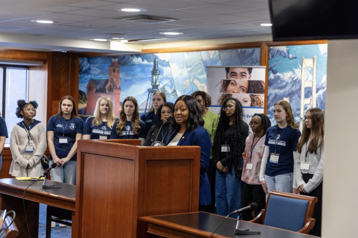 Sen. Anthony receives the Legislative Award from representatives of the School-Community Health Alliance of Michigan. She speaks at the podium with school aged children behind her