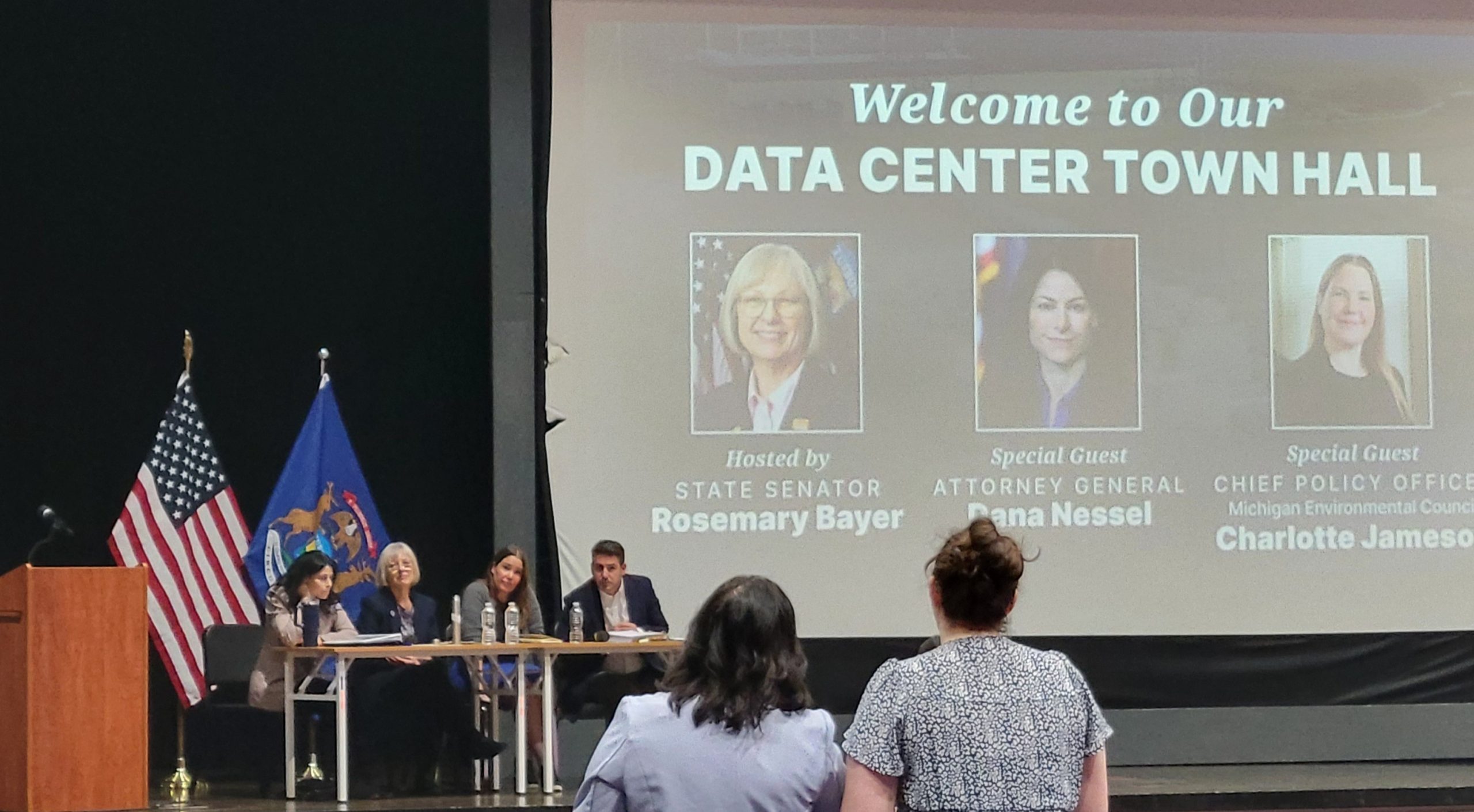 Sen Bayer joined by Attorney General Dana Nessel at her Data Center Town Hall. They are sitting at a table with a welcome message projected on a screen behind them