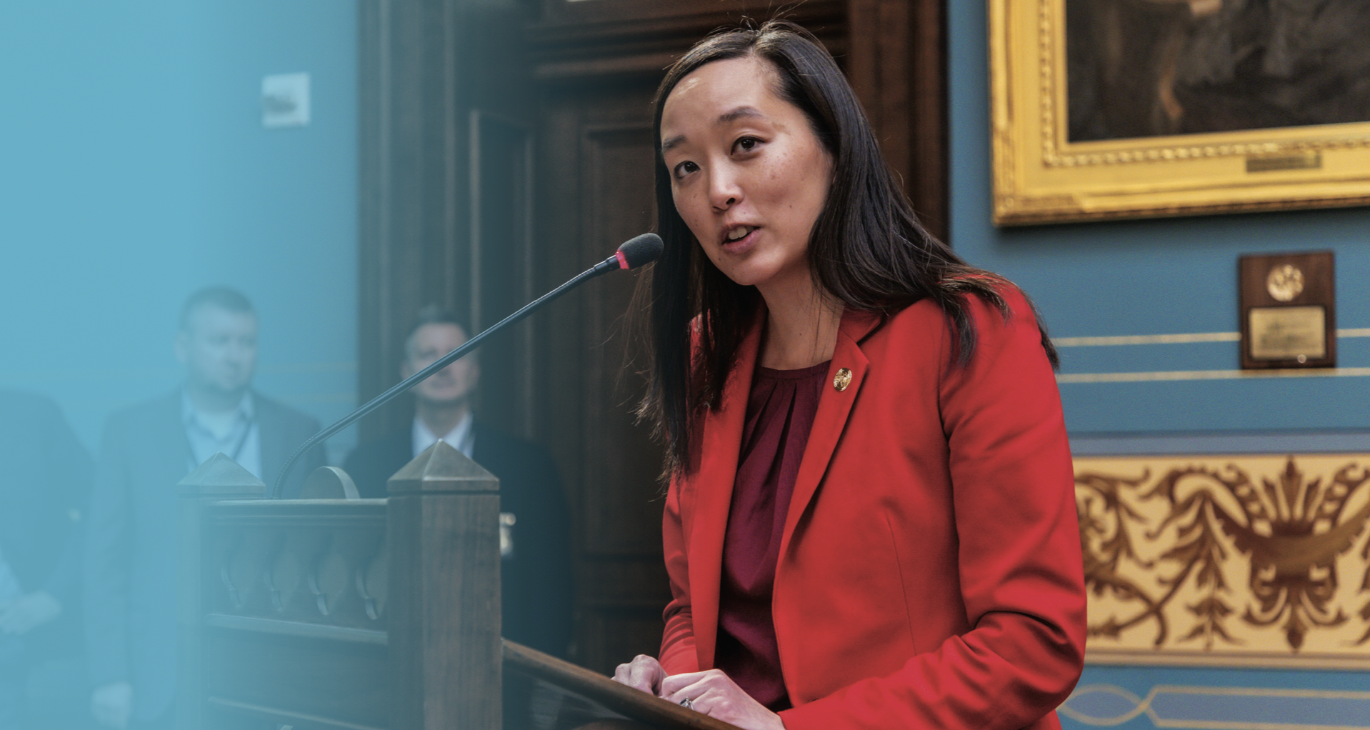 Senator Chang speaking on the senate floor wearing a red jacket