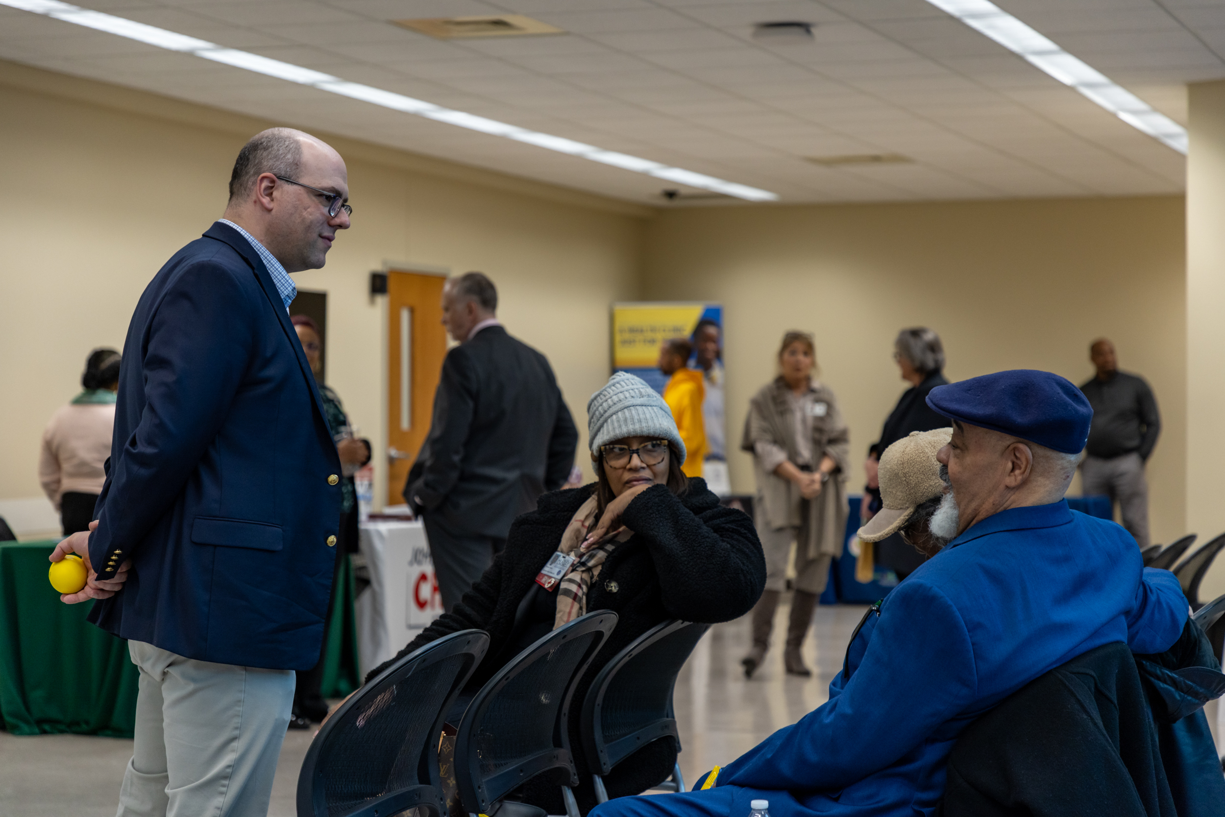 Senator Cherry speaking with two seated constituents at the Health Care Forum