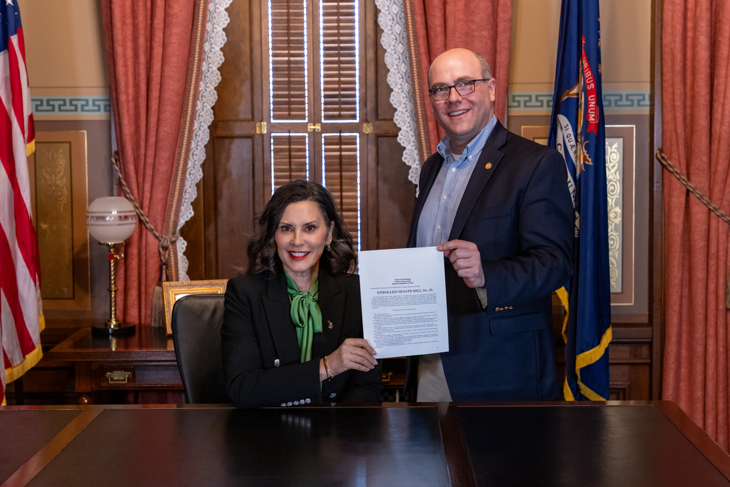 Senator Cherry and Governor Whitmer holding up the signed Senate Bill 25