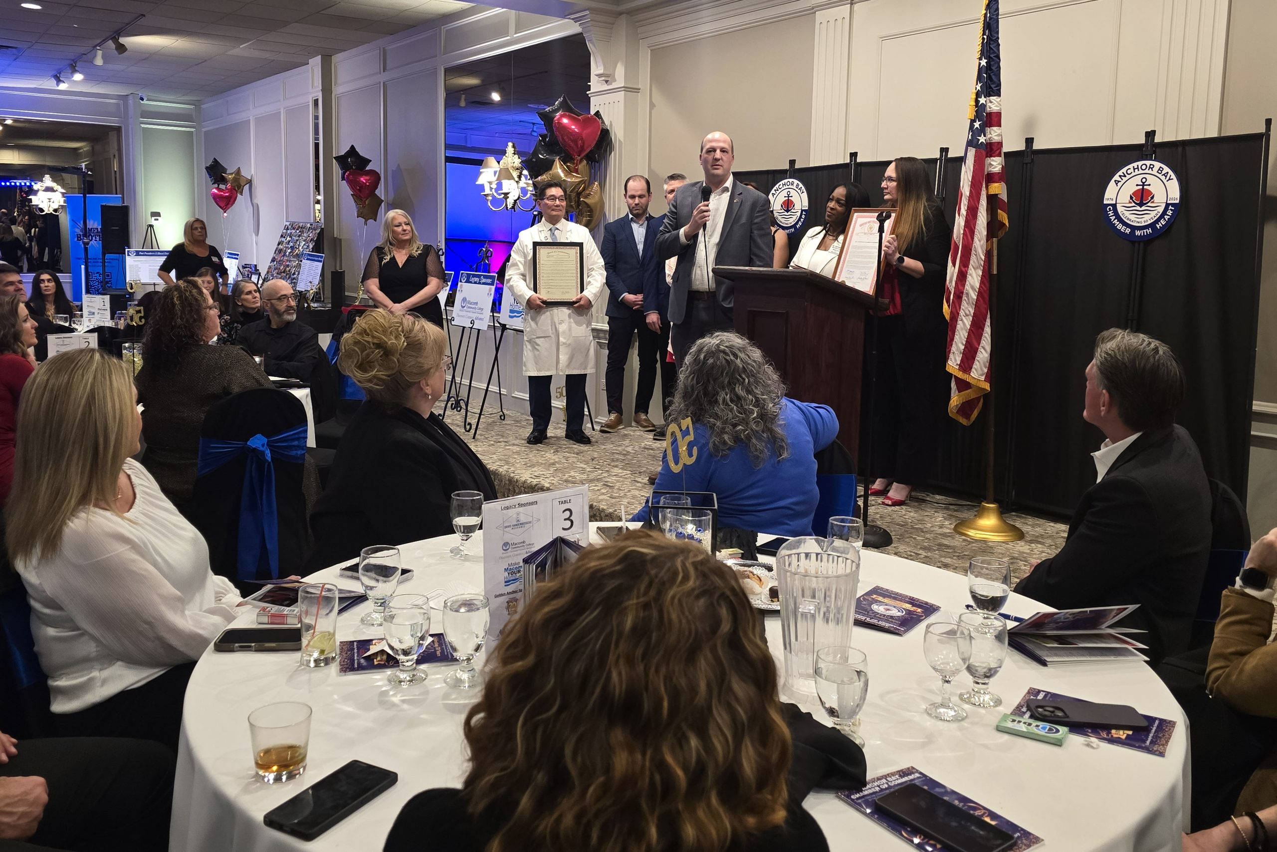 Sen Hertel speaking at a podium to a crowd of local leaders and small business owners at the Anchor Bay Chamber's 50th Anniversary 