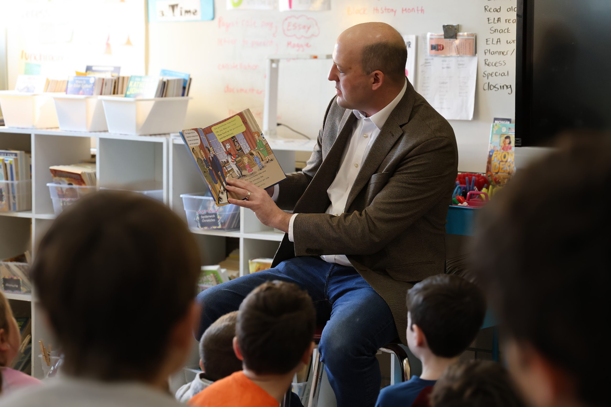 Senator Hertel reading to a group of elementary students in a classroom 