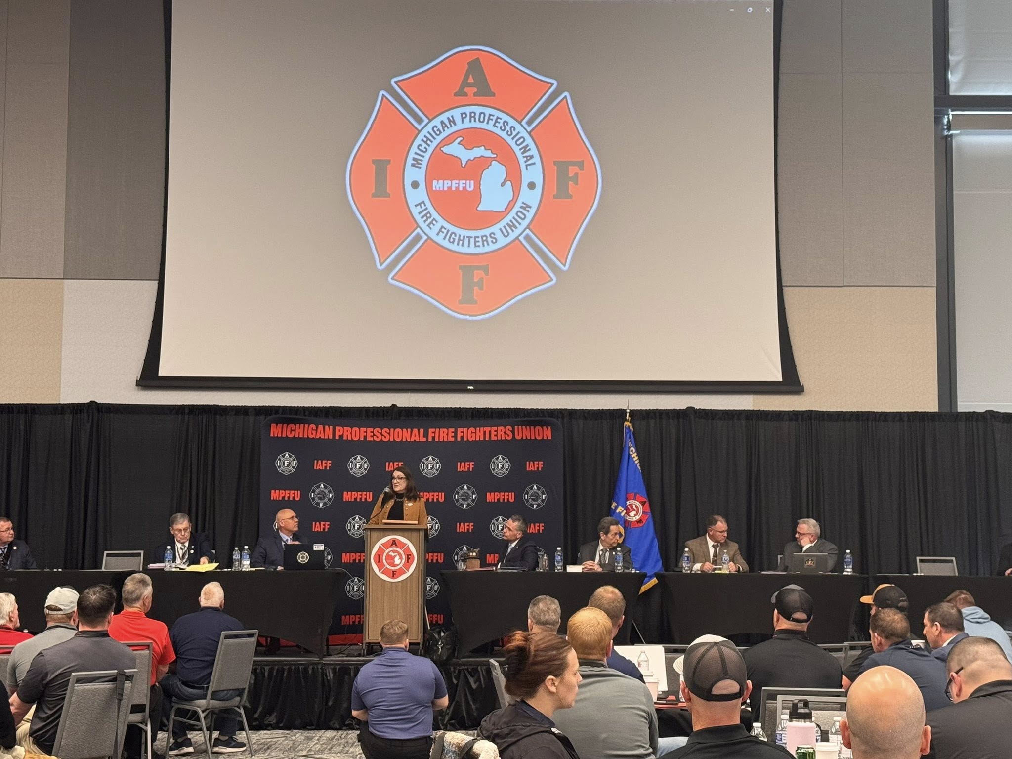 Senator Klinefelt on a stage speaking to a crowd of firefighters