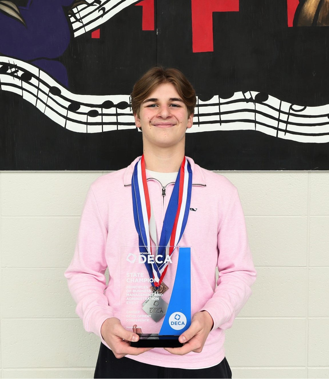 Matt Maseo holding a Deco trophy and wearing two medals