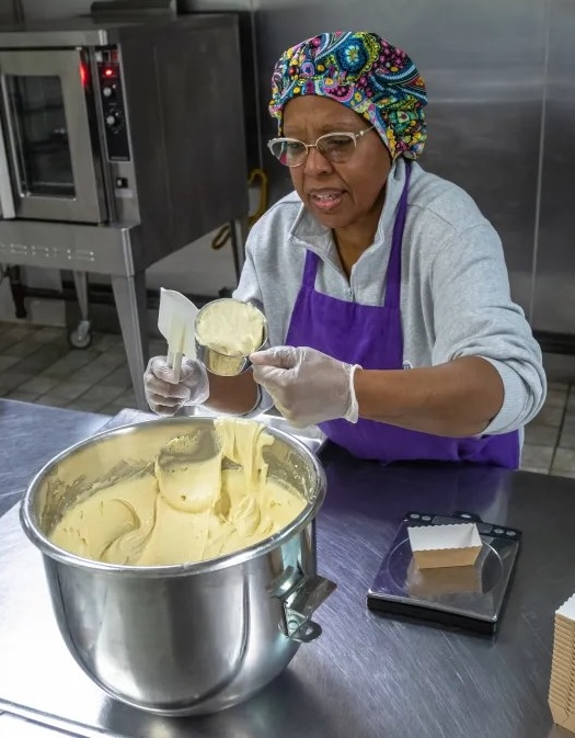 Patrice Davis measuring baking ingredients out of a large metal bowl