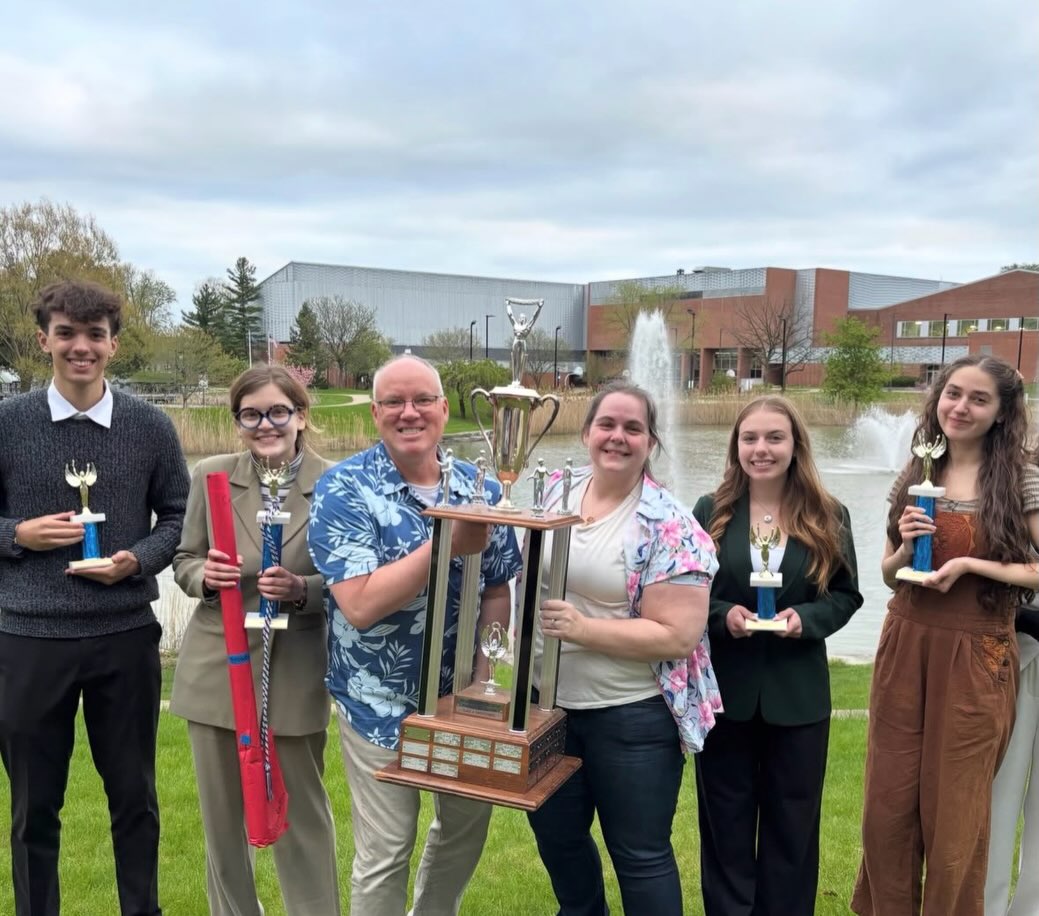 Birmingham Groves High School Forensics team holding medals and tropies from a forensics competition