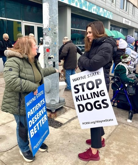 Sen Polehanki holding a sign reading "Wayne State Stop Killing Dogs" She's speaking to a woman also holding a sign