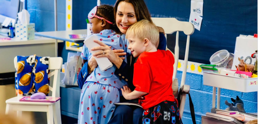 Two children hugging Sen Polehanki after she visits a classroom