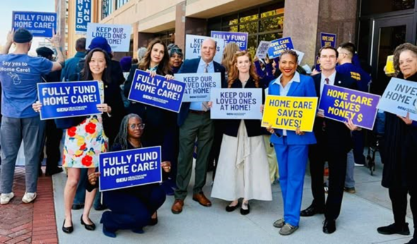 Sen Polehanki holding a sign that reads "Fully fund Home Care!" along with other state legislators