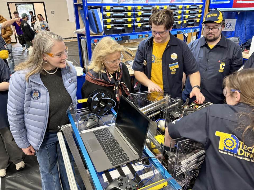 Senator Shink at First Robotics with a group of highschool students observing a robot