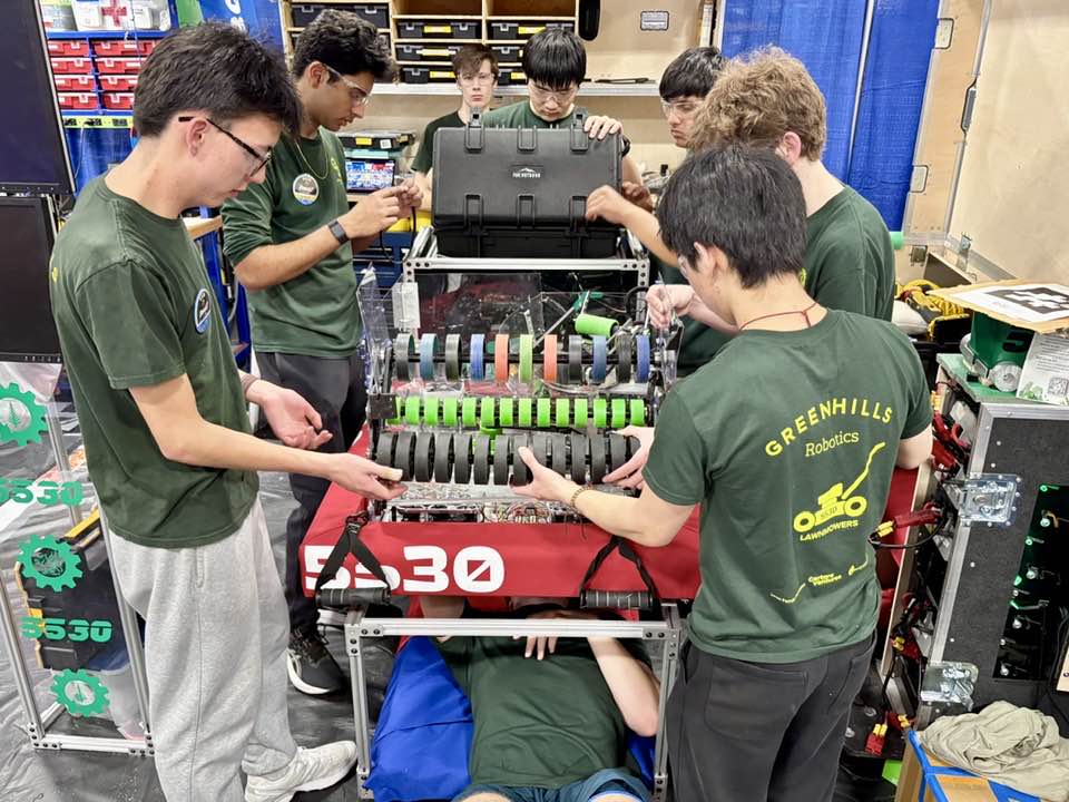A group of highschool students working on a robot at a robotics competition