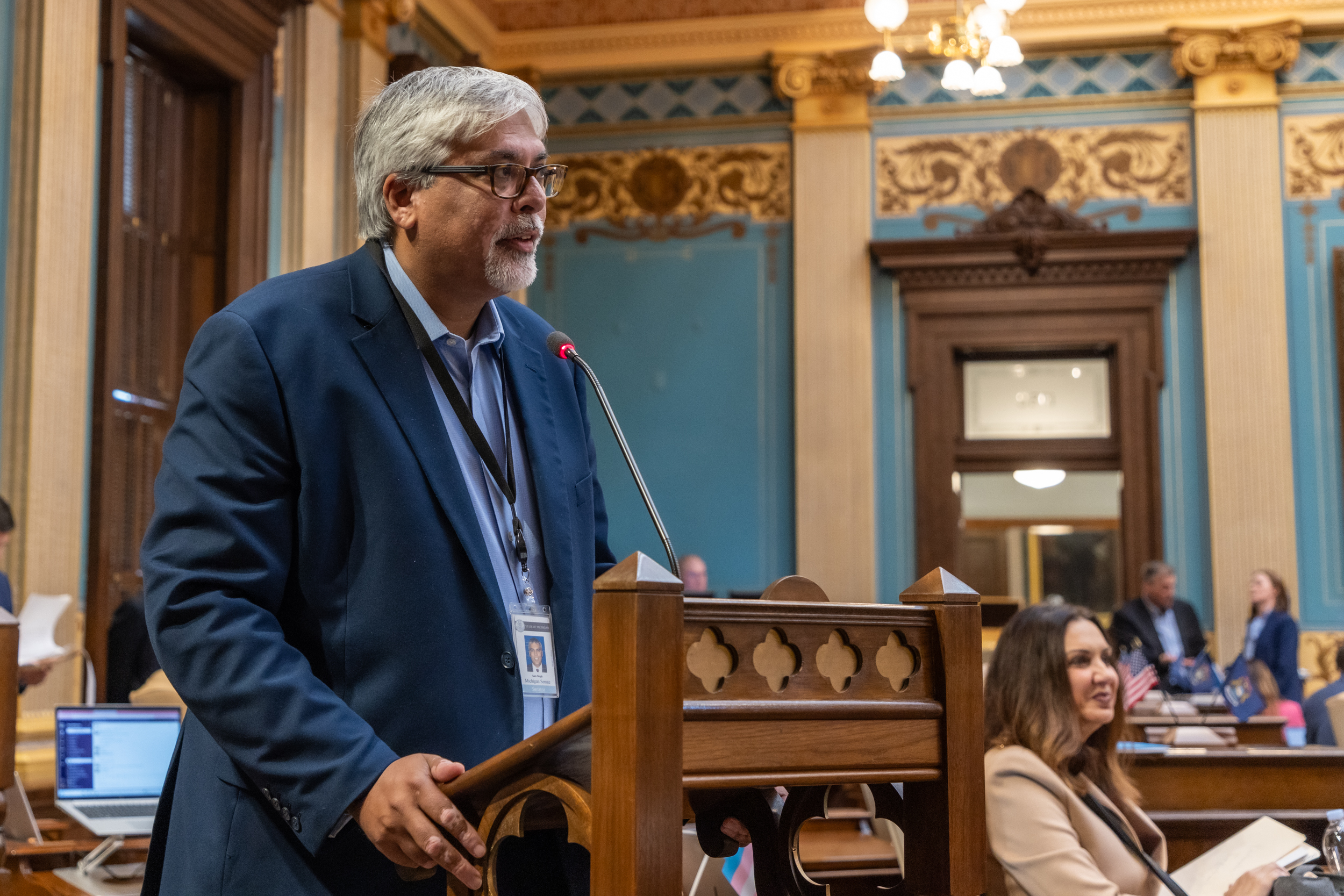 Senator Singh speaking into the microphone at the podium of the Senate Floor