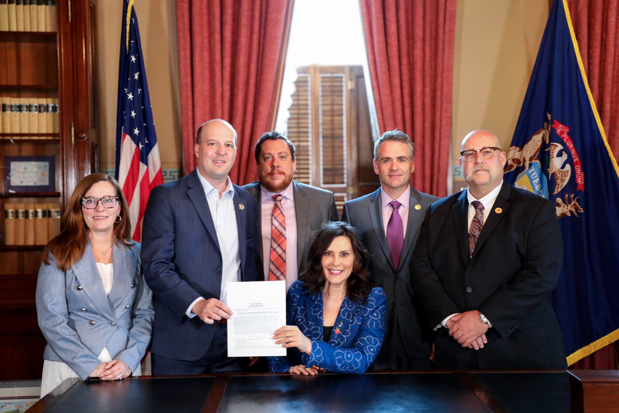 Sen. Kevin Hertel and Matt Sahr, President of the Michigan Professional Fire Fighters Union, join Gov. Gretchen Whitmer as she signs legislation to help combat the state's shortage of paramedics.